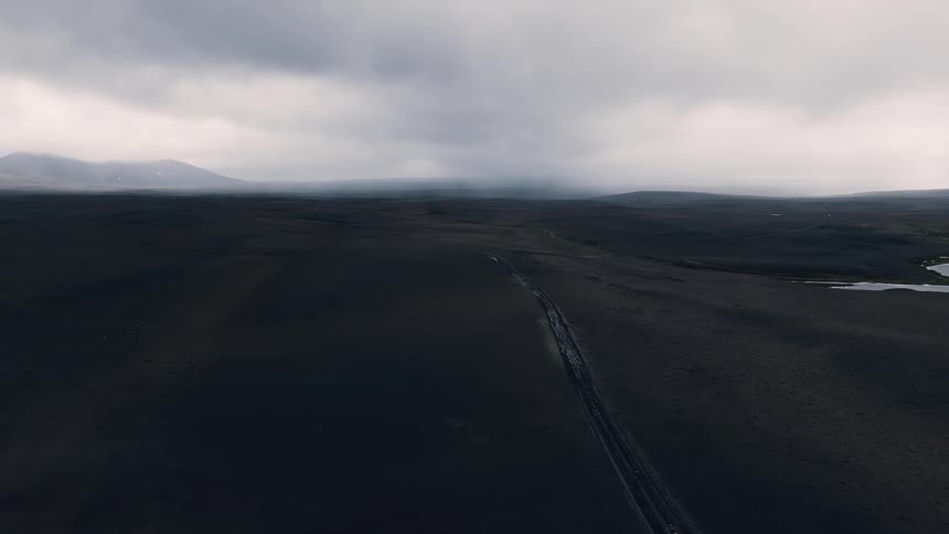 Vast dark landscape stretches beneath a cloudy and atmospheric sky