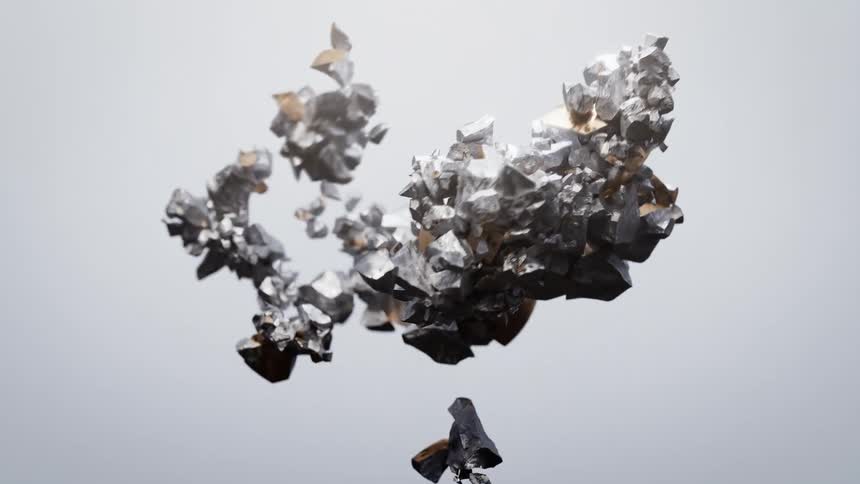 A shiny bronzecolored egg shatters into many pieces of jagged silver and goldtoned metallic shards that float against a smooth gray background