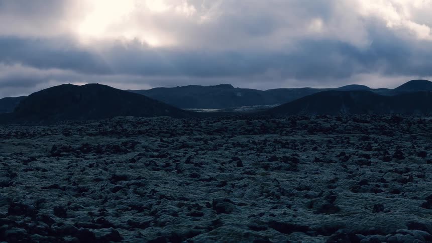 Dark rocky field under a dramatic sky at dusk