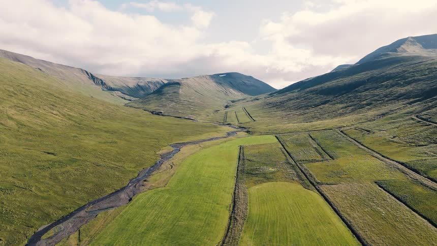 Verdant valley with a winding stream between gentle hills