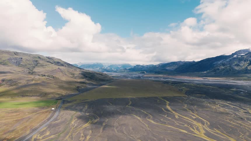 A countryside road stretches across wide open land at midday