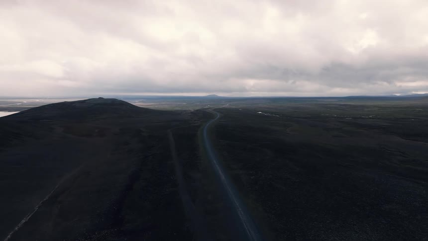 A countryside road curves over a hill surrounded by vast open land