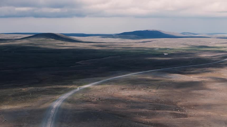 Winding road crossing an arid landscape under a cloudy sky