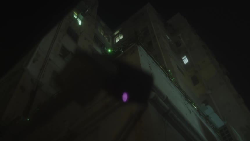 A highrise residential building is seen through a car windshield at night with lights glowing from its rooms