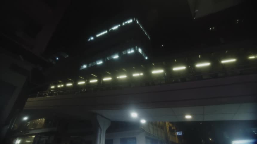 People move along a raised path in downtown at night