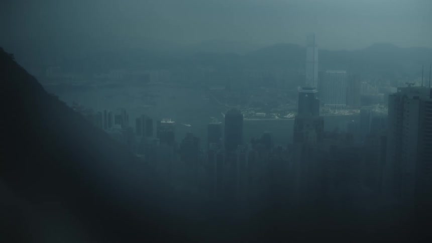 Dense fog obscures the skyscrapers in a city bordered by the mountains