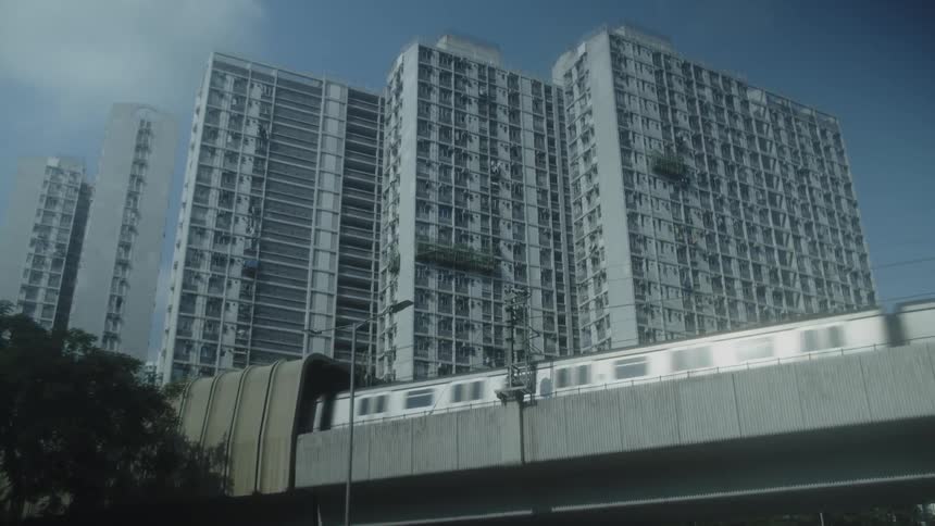 Passenger train enters a tunnel on a raised railway passing by large apartment buildings