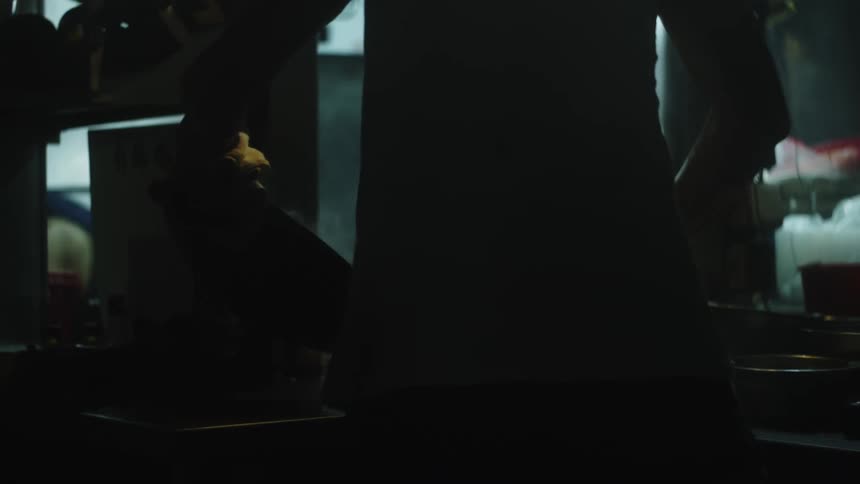A man is in the kitchen cooking stirring and frying food in a pan