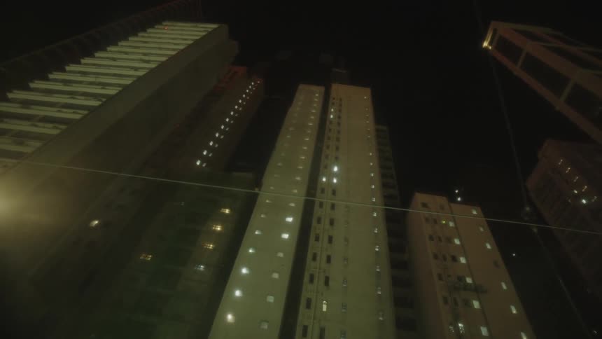 Tall buildings lit up at night seen from a low angle