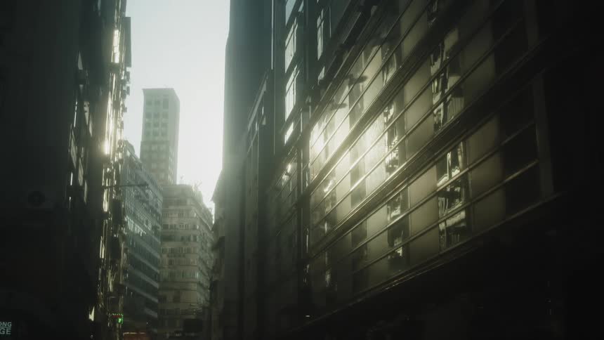 Sunlight reflects on the faades of tall buildings along a narrow city street