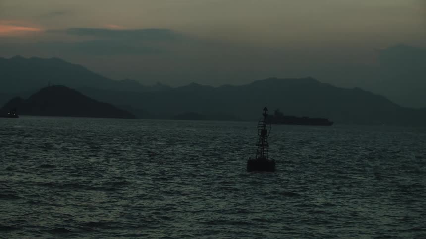 The small beacon floats in the water off the shore