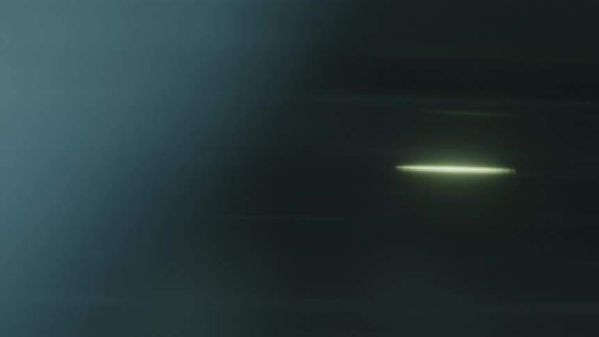 A dark tealtoned background shows a horizontal bright yellowwhite lens flare that streaks across the screen from left to right creating an anamorphic light leak effect
