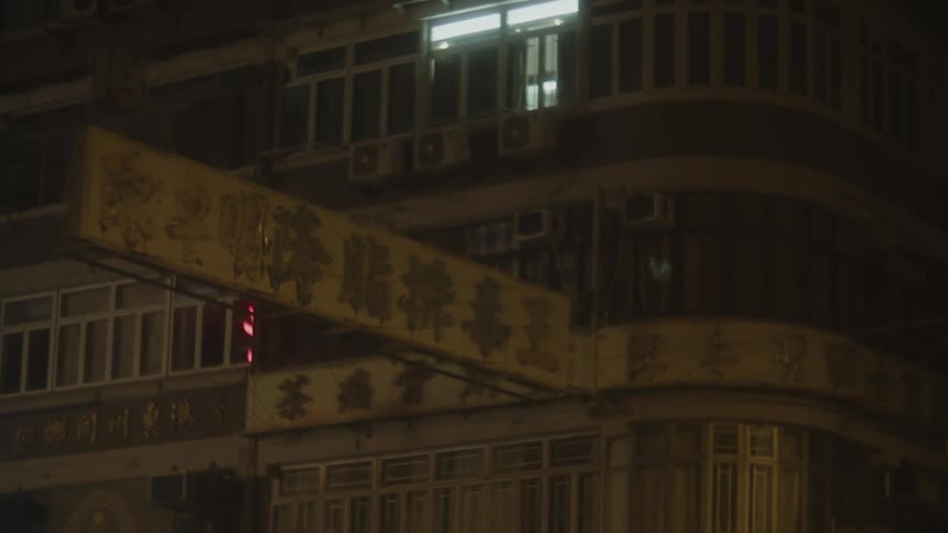 A building with old chinese shop signs faintly glowing at night