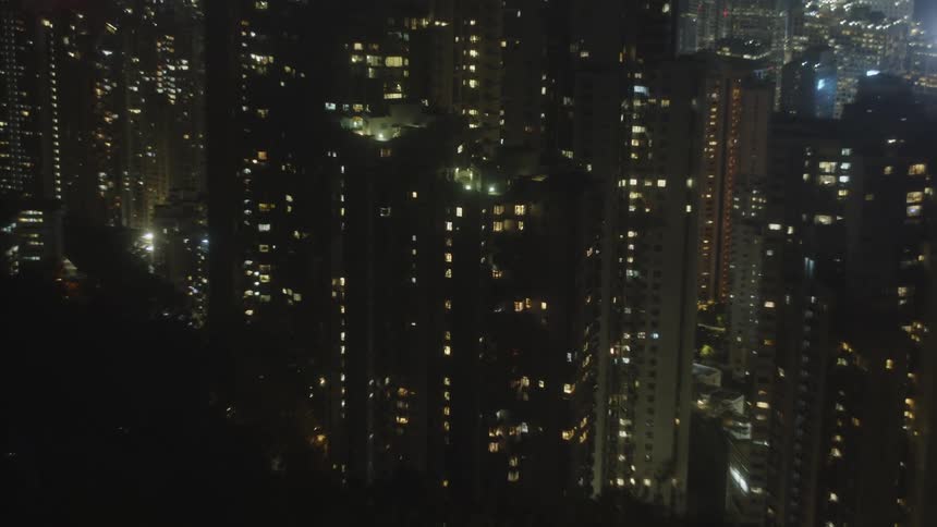 A dense urban cityscape at night with countless windows illuminating the tall buildings in a captivating display of lights