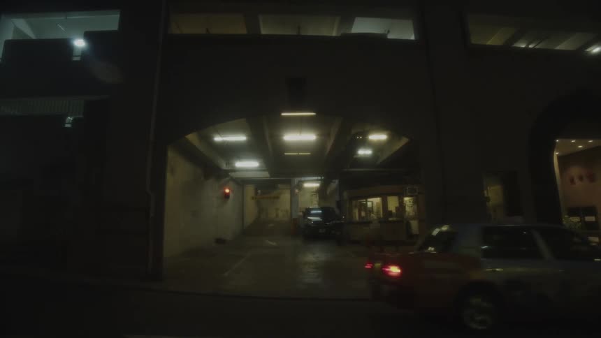 Entrance of a parking garage with cars under dim lights at night