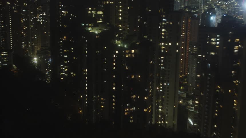 A city skyline at night with skyscrapers illuminated by bright lights against the dark sky
