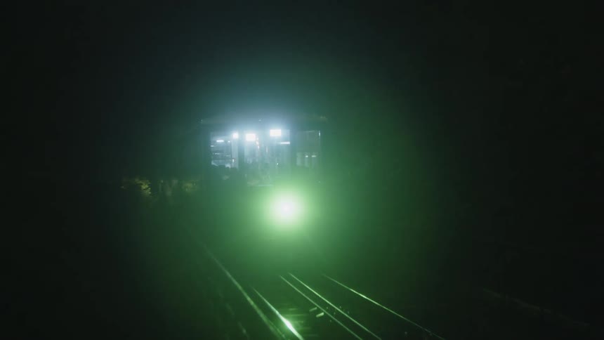 A train races along the tracks at night its lights glowing brightly in the darkness