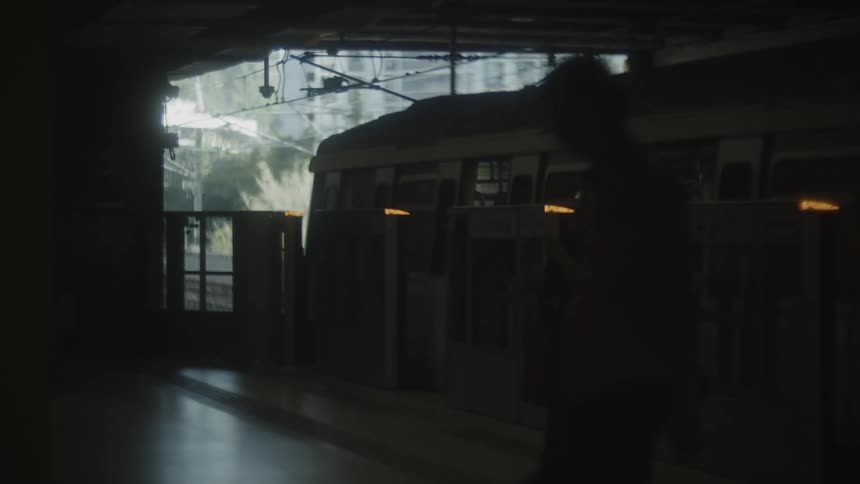 Silhouettes of people move on a platform beside a stopped train