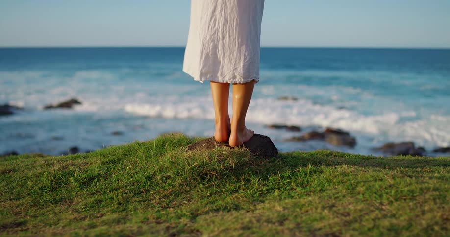 Bare feet on the grass by the sea under the soft light of late afternoon