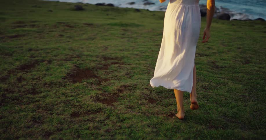 The woman skips on the grass by the shore