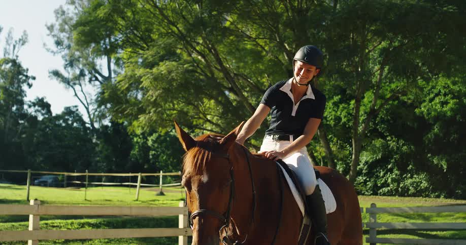 A young woman wearing a helmet rides a horse across the grassland at midday