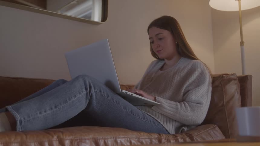 The woman is typing on her laptop and looking up and down