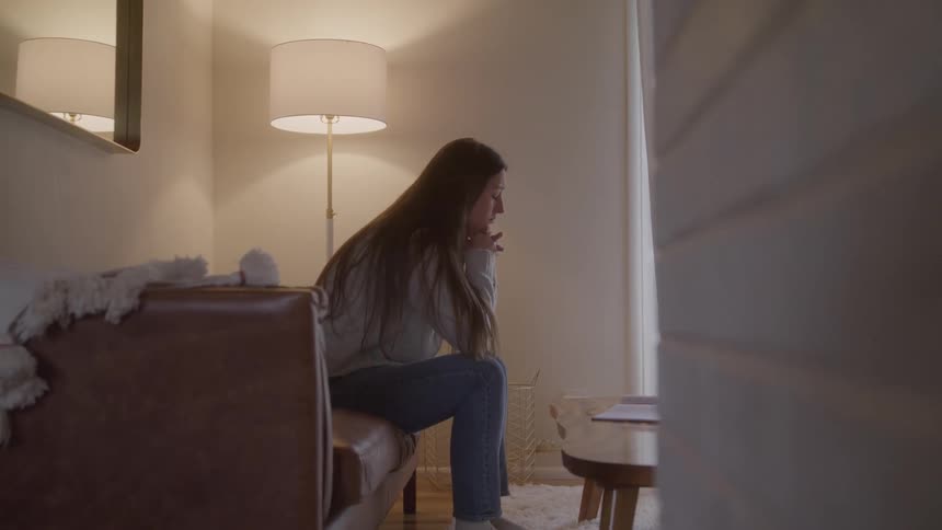 Woman sitting on the sofa gestures while speaking toward the window