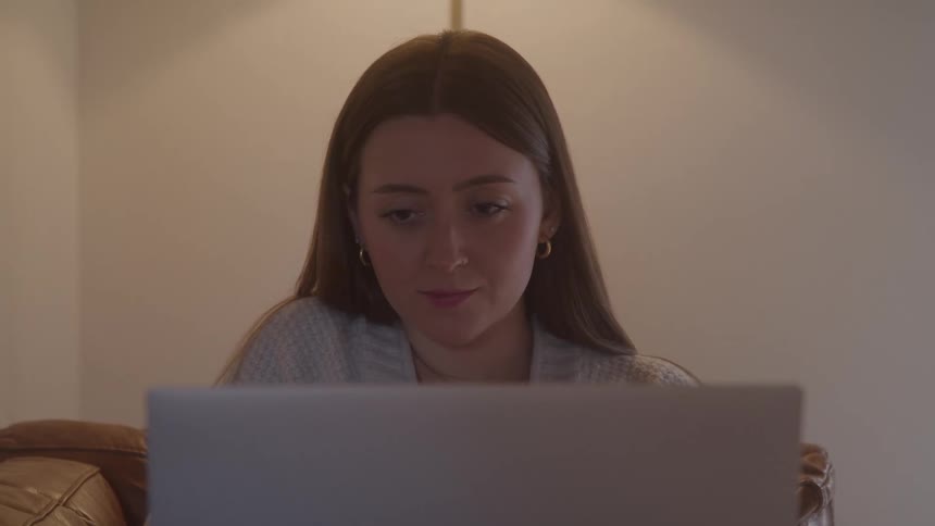 A woman sitting and working on a laptop indoors