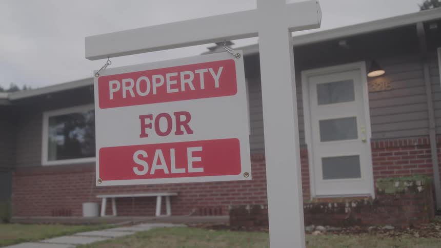 A red and white for sale sign is in front of the home