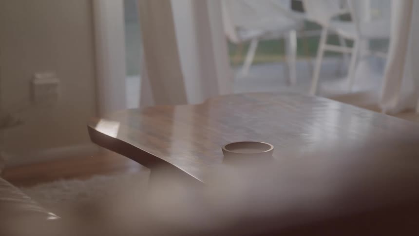 The woman takes the cup of coffee off the coffee table
