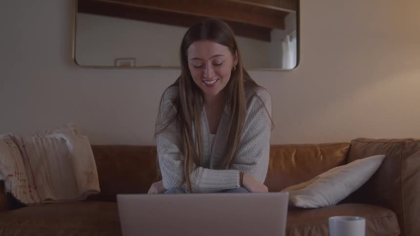 The woman is happy while talking to someone on her laptop