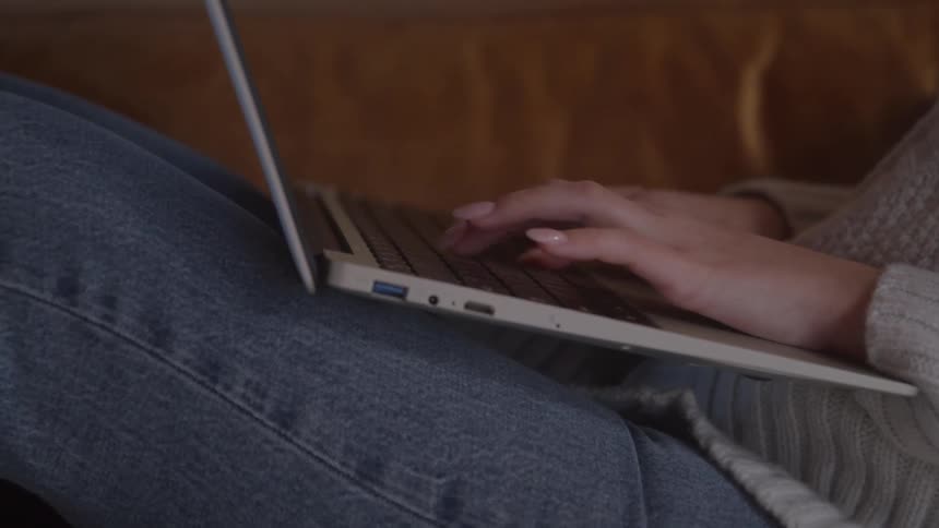 Close up of a young woman using a laptop computer while sitting on a couch in a living room