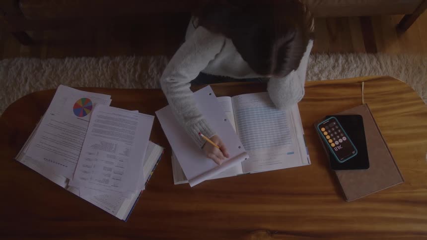 The woman is studying and writing on a pad