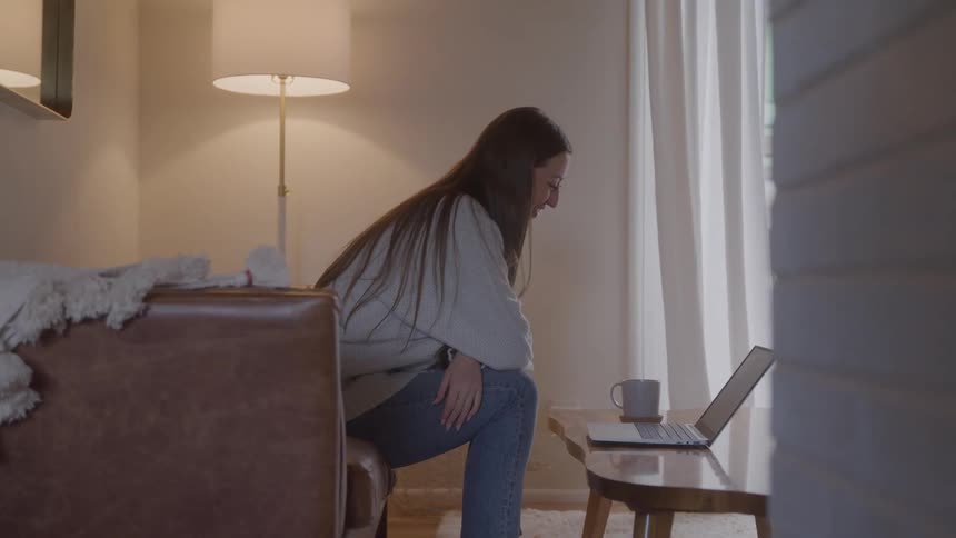 The woman waves at her laptop while on a video call