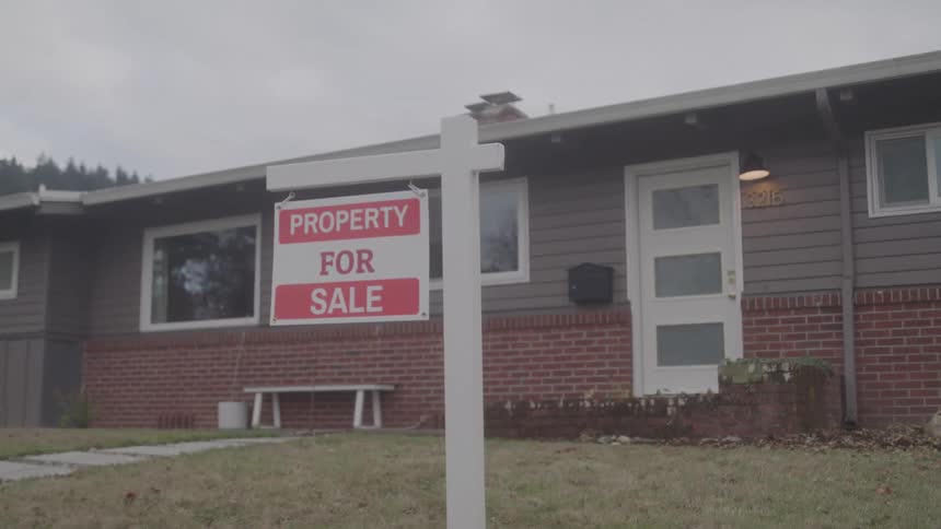 A red and white street sign for the sale of a property outdoors in a suburban area at sunset