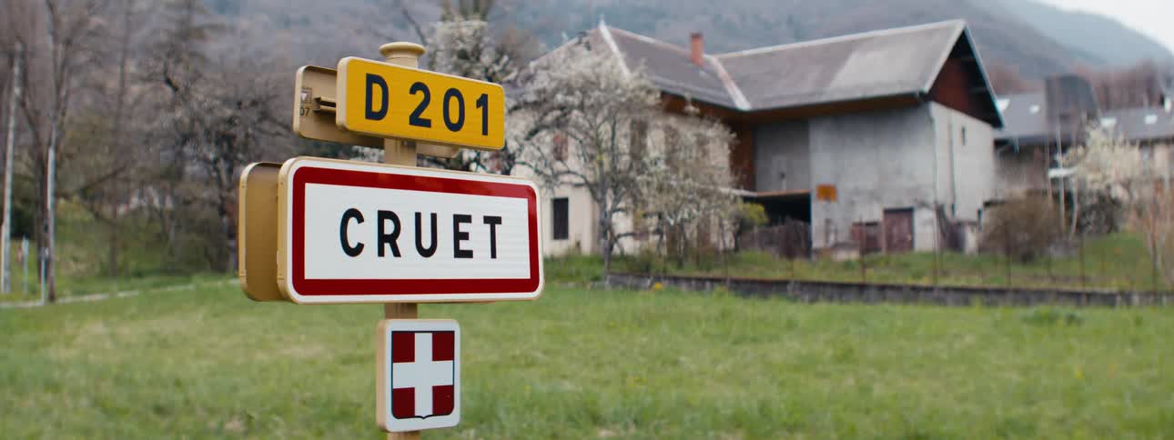 A sign stands on the lawn in front of a residential building in a suburban area