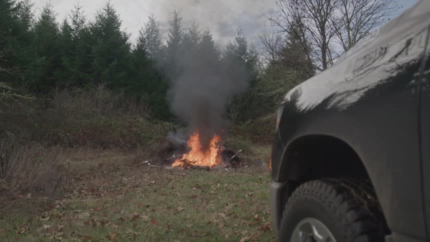 A group of items burning on the floor outdoors in a forest area during daytime
