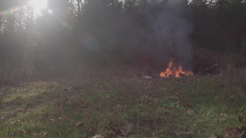 Dark smoke rises from the bonfire