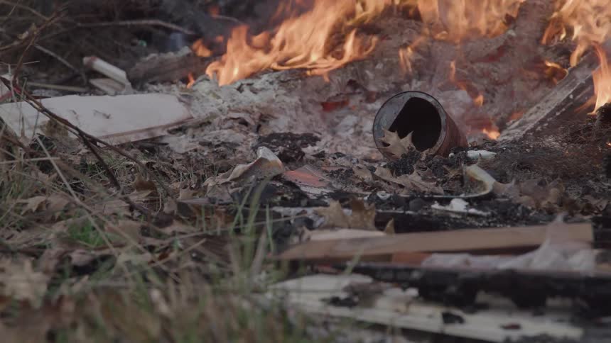 Fire burns through debris and dry leaves scattered on the ground