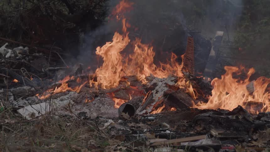 Intense flames consume wood and debris in an open area
