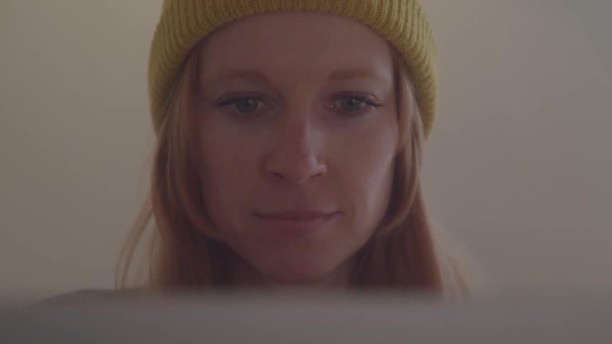 Woman wearing a yellow beanie looks attentively at something ahead