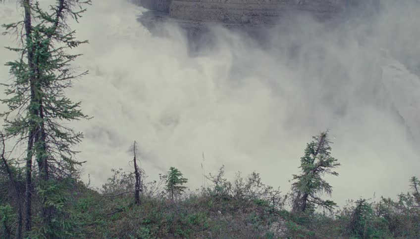 Turbulent water plunges between rocks surrounded by dense vegetation