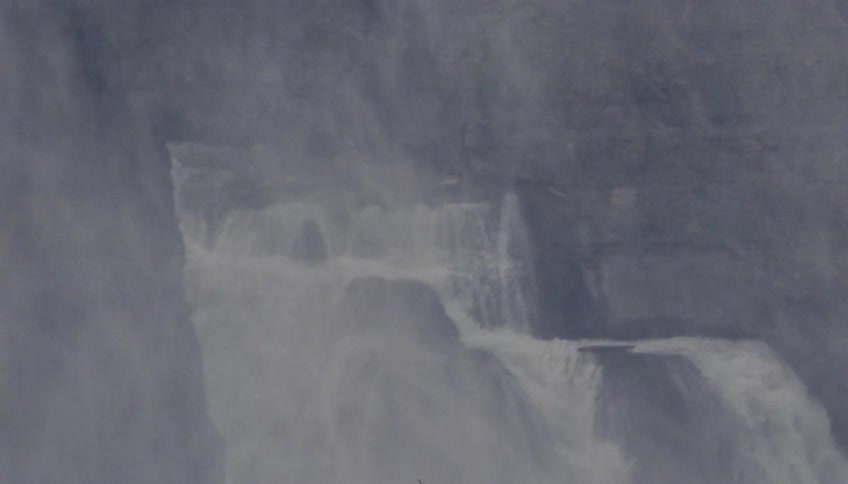 Powerful waterfall plunges between cliffs creating intense mist