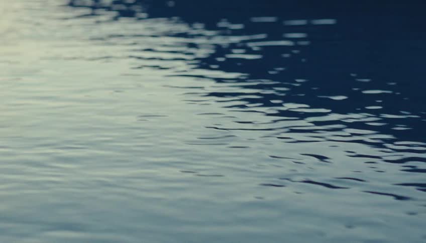 Gentle ripples form on the bluish water surface at dusk