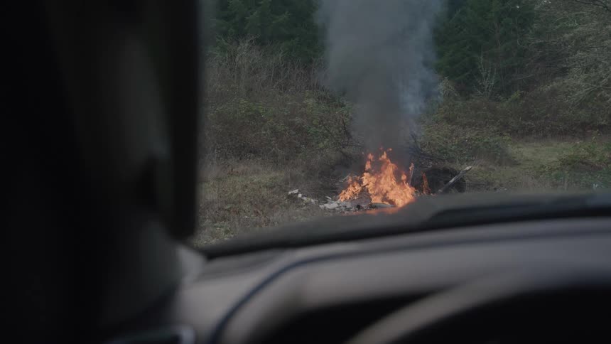A group of items burning on the floor in a forest area during daytime