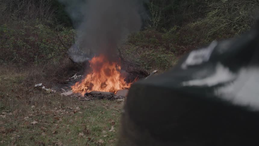 The trash is burning by the forest