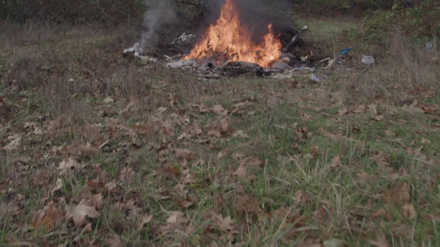 Intense fire burns branches and debris in an area covered with dry leaves