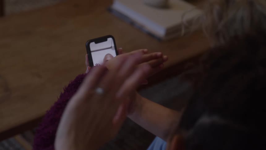 The woman and child wave to a man on the cell phone