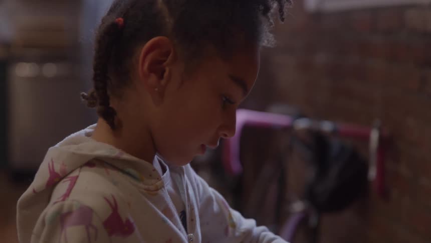 Girl fits colorful shapes into board on wooden table