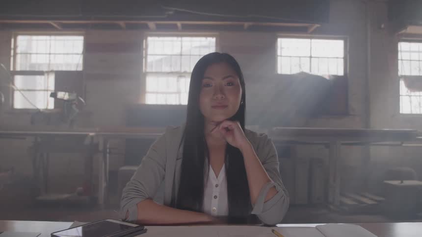The woman smiles while sitting in the workshop